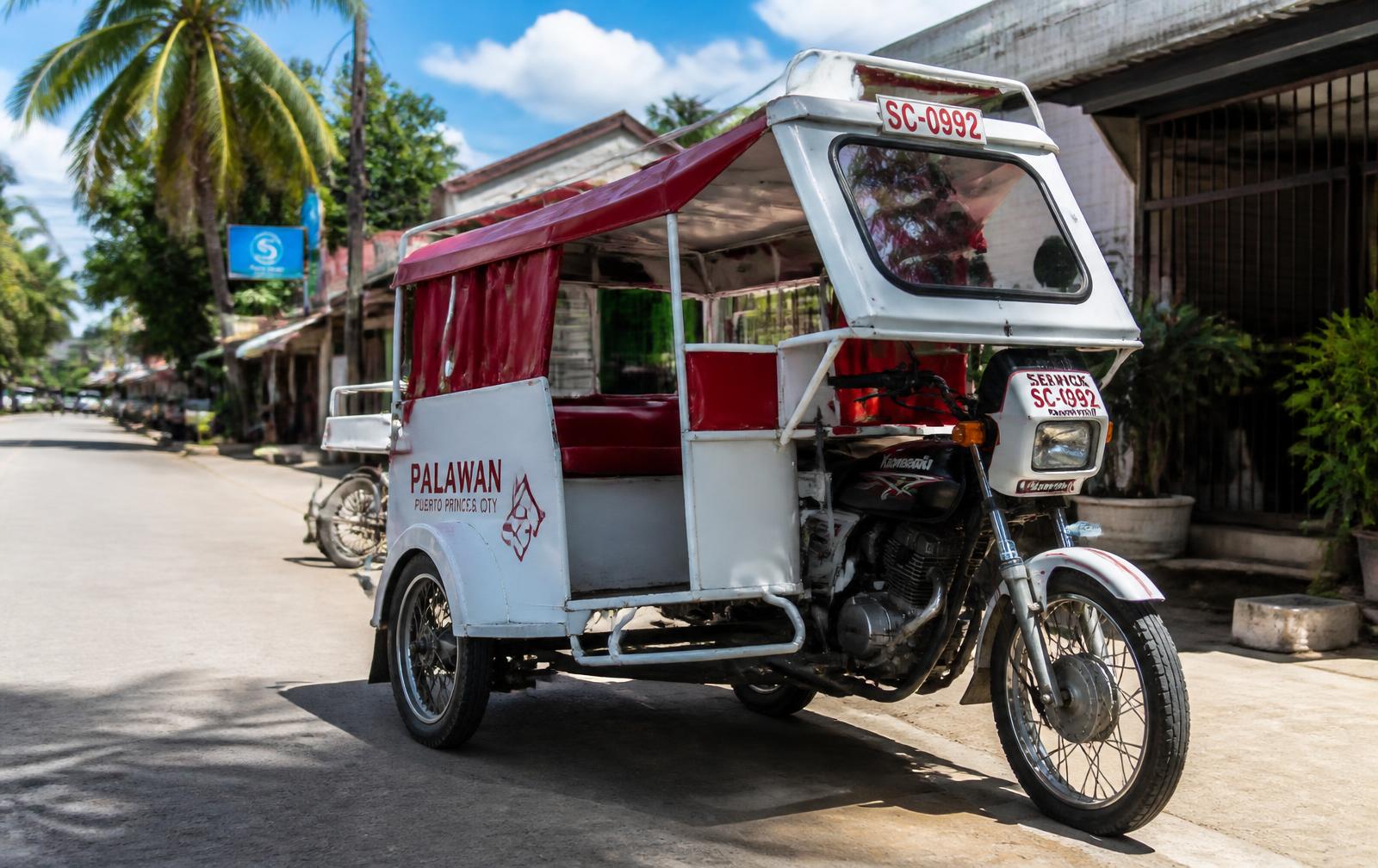 Passenger tricycle parked on a sunny palm-lined street in the Philippines